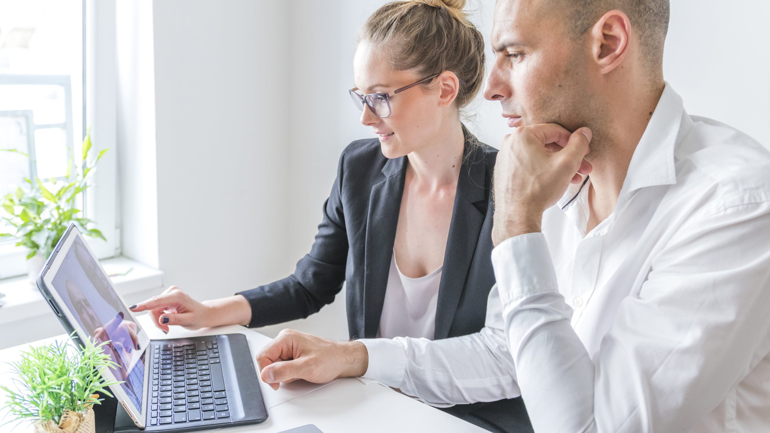 two businesspeople working laptop workplace min